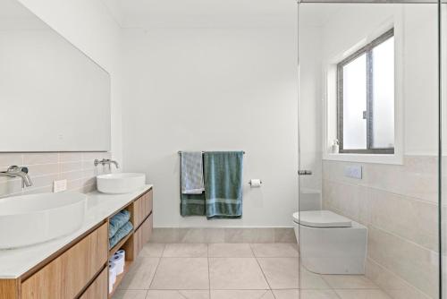 a white bathroom with a sink and a toilet at Callala Haven - Pet Friendly with Fire Pit in Callala Bay