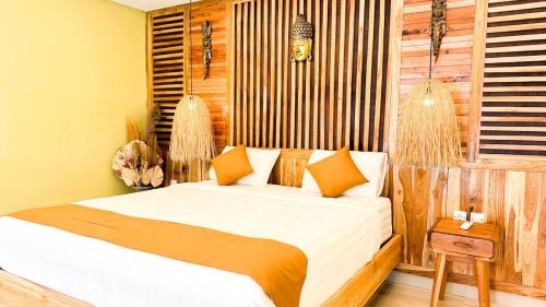 a bedroom with a bed with white sheets and orange pillows at Tropical Boho Loft Villa with Sofa Beds in Canggu