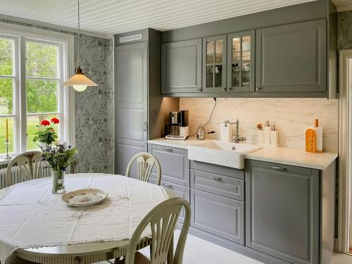 a kitchen with green cabinets and a table and a sink at Historic Countryside Home Near Lake In Ekeryd in Svängsta