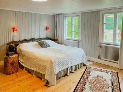 a bedroom with a bed and two windows at Historic Countryside Home Near Lake In Ekeryd in Svängsta