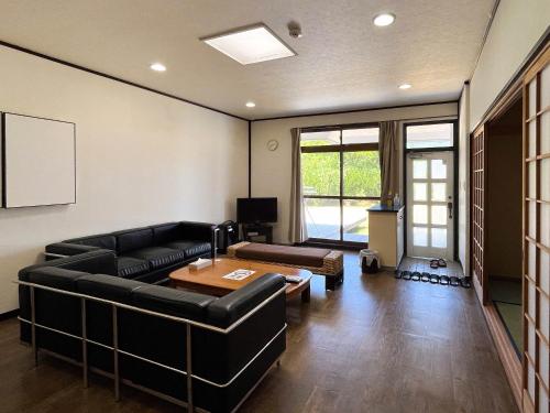 a living room with a black couch and a table at Sea Tiger Island Inn Shodoshima in Shodoshima