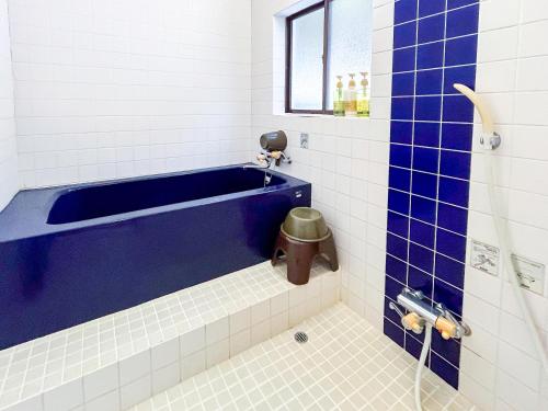 a bathroom with a blue tub and a toilet at Sea Tiger Island Inn Shodoshima in Shodoshima