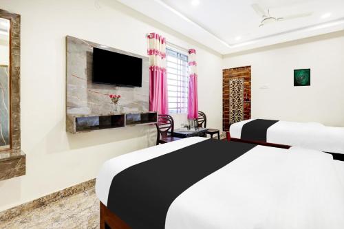 a bedroom with two beds and a flat screen tv at Super Hotel O Vizianagaram Near Railway Station in Vizianagram City