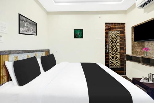 a bedroom with a black and white bed and a tv at Super Hotel O Vizianagaram Near Railway Station in Vizianagram City