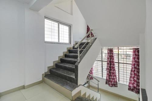 a staircase in a white room with two windows at Hotel O Bhekrai Nagar Bus Terminal Formerly Silver Star in Phūrsungi
