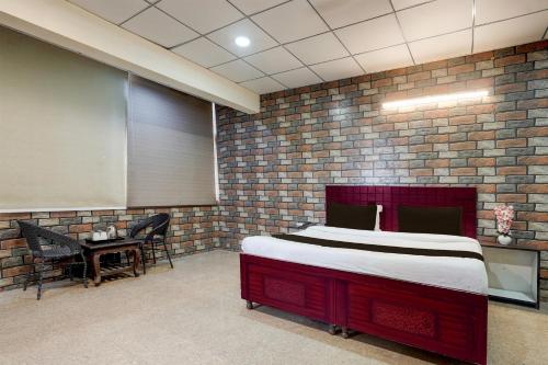 a bedroom with a bed and a table with chairs at Super Hotel O Sector 58 Mohali Formerly Hotel Alpha in Mohali