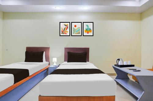a room with two beds and a desk in it at Collection O Nellore Subbareddy Government Hospital Formerly Hotel Rama Royal in Nellore