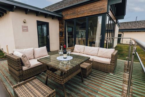 a patio with a table and wicker furniture on a deck at Betony in Bamburgh