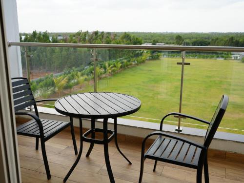 a table and chairs on a balcony with a view at Sportico Resort Bangalore in Mālūr