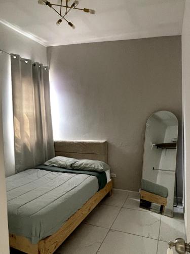 a small bedroom with a bed and a mirror at Acogedor departamento cerca de la X in Arena