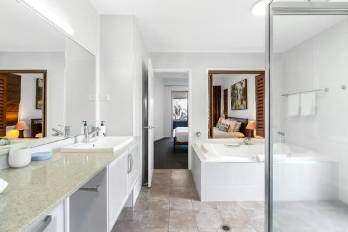 a white bathroom with two sinks and two mirrors at The Marron Bloom - Beachfront Boutique Bliss in Palm Cove