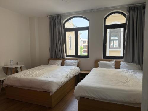 deux lits dans une chambre avec deux fenêtres dans l'établissement Homestay Ocean City, Kinh Đô 5-15, à Ðình Loan