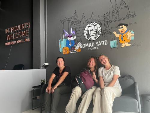 three women sitting on a couch in a room at Nomad Yard Hostel in Bangkok