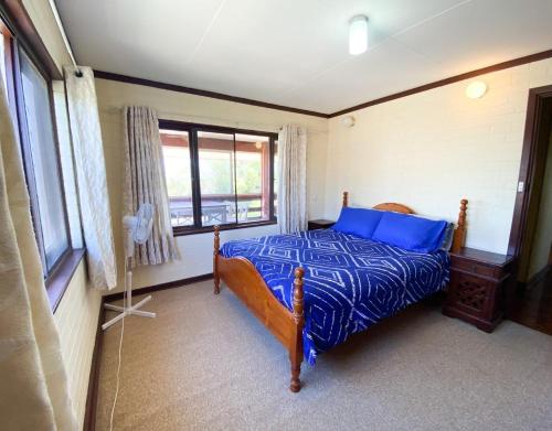 a bedroom with a bed with blue sheets and a window at Double View in Lancelin