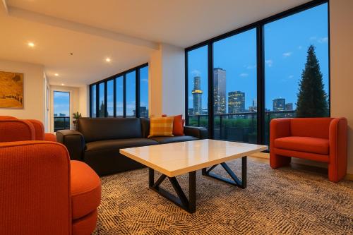 a living room with couches and chairs and a table at Aura on Flinders Serviced Apartments in Melbourne