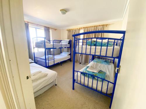 a room with three bunk beds and a window at Lancelin Beach house in Lancelin