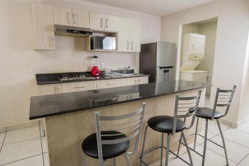 a kitchen with a counter and three bar stools at Lodging centrally located near H.Civil, CUCS, IMSS in Guadalajara