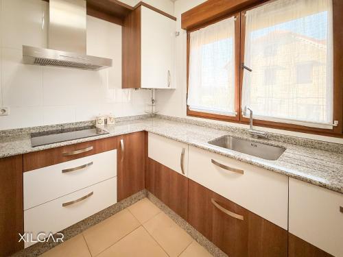 a kitchen with white cabinets and a sink and a window at Xilgar - O Vimbieiro Chalet in Sanxenxo