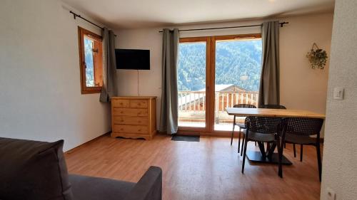 Una sala de estar con una mesa y sillas y una ventana. en Appartement cosy vue panoramique Orelle les 3 Vallées, en Orelle