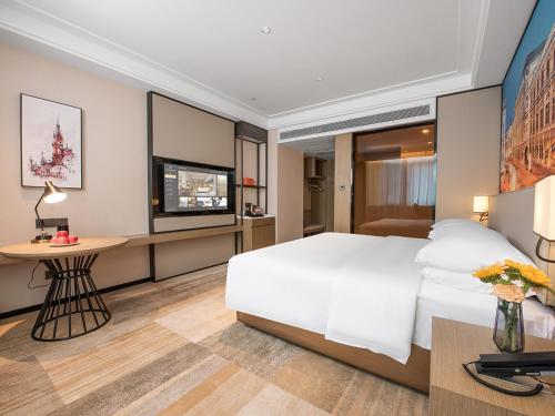 a bedroom with a large white bed and a desk at Vienna International Hotel Xi'an Jinye Road Branch in Xi'an