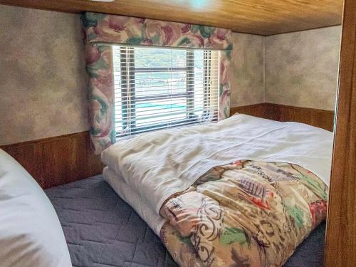a small bedroom with a bed and a window at Sea Tiger Island Inn Shodoshima in Shodoshima