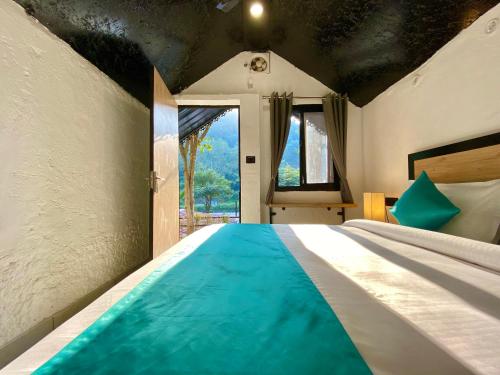 a bedroom with a large bed with a blue blanket at Euphoric Resort ,Mohanchatti in Rishīkesh
