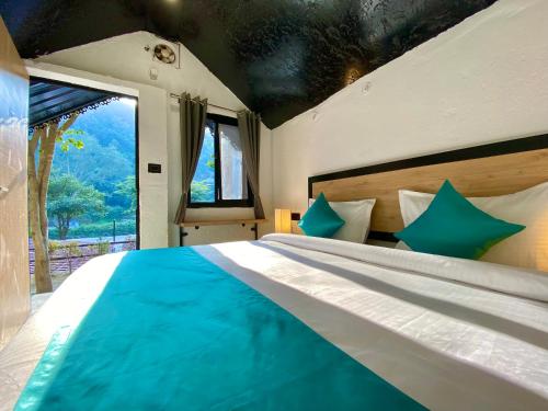 a bedroom with a large bed with a large window at Euphoric Resort ,Mohanchatti in Rishīkesh