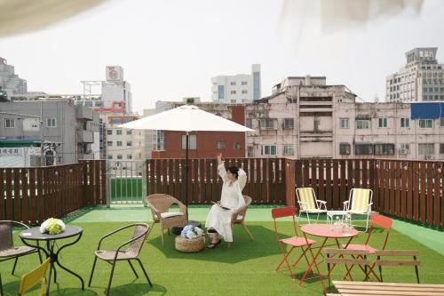 a woman sitting on a balcony with an umbrella at D A L Premium Capsule Hotel in Seoul