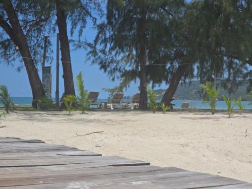 a wooden walkway on a beach with chairs and trees at White Beach Resort Longset in Koh Rong Island