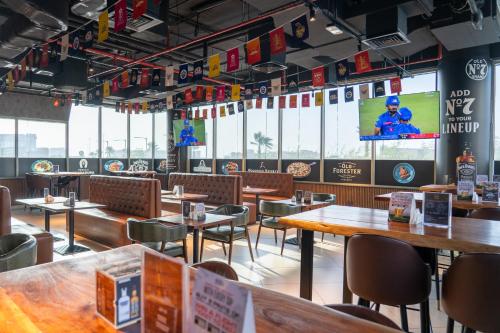 a restaurant with tables and chairs and a screen at VOGO Grand Hotel Formerly Best Western Plus Hotel Dubai Academic City in Dubai