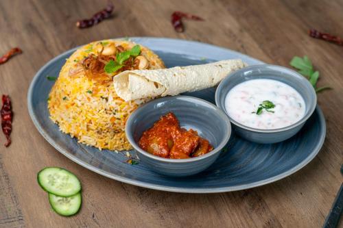 a plate of food with rice and a burrito and dip at VOGO Grand Hotel Formerly Best Western Plus Hotel Dubai Academic City in Dubai