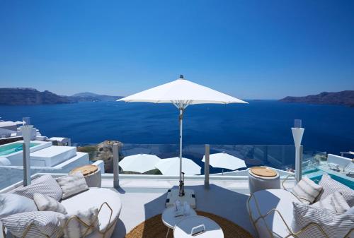 a patio with chairs and an umbrella and a pool at Filotera Suites in Oia