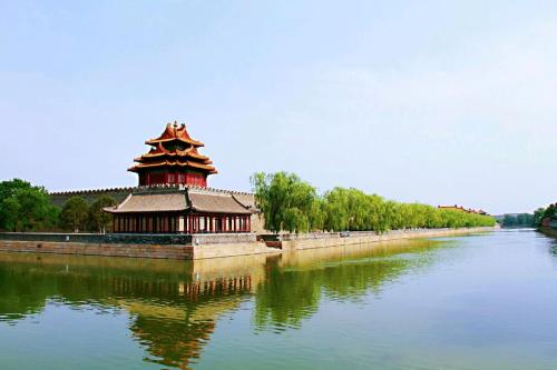 a building sitting on the side of a river at Yinzhuo Hotel - New Chinese decoration, free late-night supplies, free fruit, water and free snacks, close to the International Convention and Exhibition Center, Embassy, Sanlitun, Bird's Nest, close to Sanyuan Bridge of Metro Line 10 and Airport Line in Beijing
