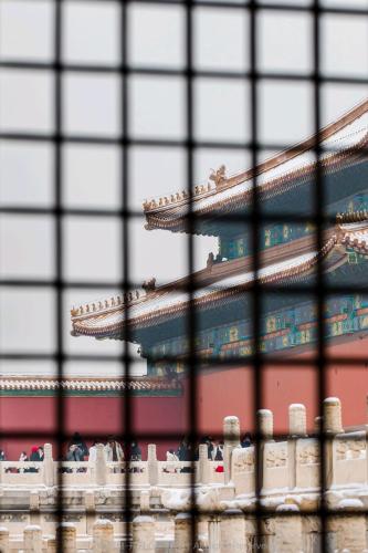 a view of a chinese building through a fence at Yinzhuo Hotel - New Chinese decoration, free late-night supplies, free fruit, water and free snacks, close to the International Convention and Exhibition Center, Embassy, Sanlitun, Bird's Nest, close to Sanyuan Bridge of Metro Line 10 and Airport Line in Beijing