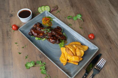 a plate of food with meat and fries on a table at VOGO Grand Hotel Formerly Best Western Plus Hotel Dubai Academic City in Dubai