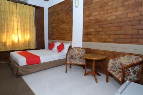 a bedroom with a bed and a table and chairs at OYO 1017 Al-inshirah Inn in Kota Bharu