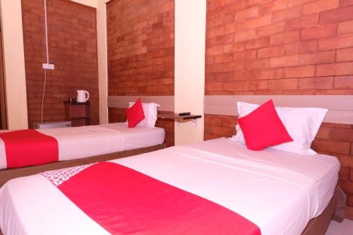 two beds in a room with red and white sheets at OYO 1017 Al-inshirah Inn in Kota Bharu
