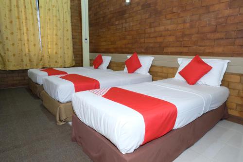 two beds in a room with red and white sheets at OYO 1017 Al-inshirah Inn in Kota Bharu
