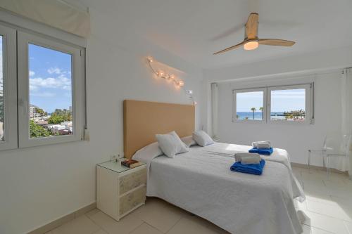 ein weißes Schlafzimmer mit einem Bett und zwei Fenstern in der Unterkunft Hawaii in Jávea