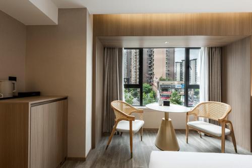 a hotel room with a table and chairs and a window at Leshan Manfu Hotel in Leshan
