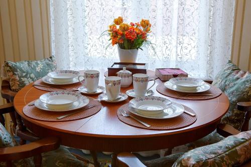 a table with plates and cups and a vase of flowers at Videviku Villa Apartments in Tallinn