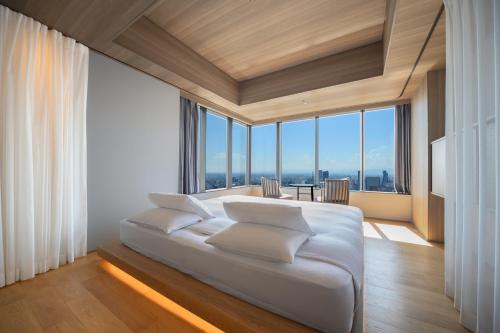 a bedroom with a white bed and large windows at The Royal Park Hotel Iconic Nagoya in Nagoya