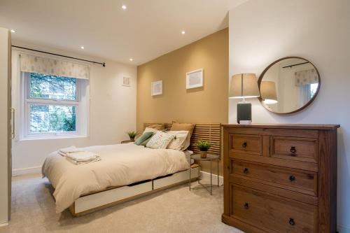 a bedroom with a bed and a mirror and a dresser at Stylish Home - Ten Mins to Central London in London