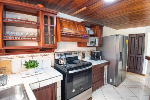 a kitchen with a black stove and a refrigerator at Tico Airport B&B in Alajuela City