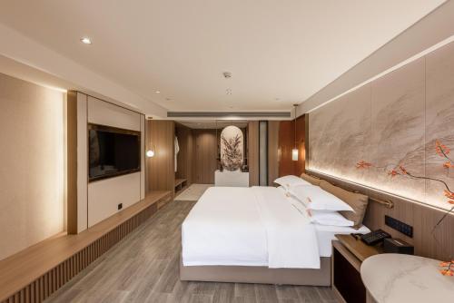 a hotel room with two beds and a flat screen tv at Leshan Manfu Hotel in Leshan