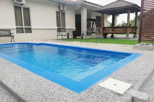 una piscina con acqua blu in un cortile di Nur Banglo Homestay Port Dickson a Kampong Baharu