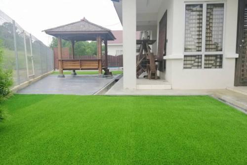 un cortile erboso con una panchina e un gazebo di Nur Banglo Homestay Port Dickson a Kampong Baharu