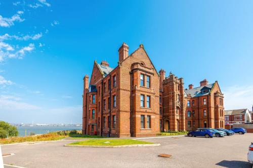 an old brick building with cars parked in a parking lot at Bright Flat with Wifi, Close to Beach! in Wallasey