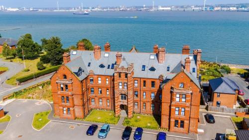 a large brick building with cars parked in front of the water at Bright Flat with Wifi, Close to Beach! in Wallasey