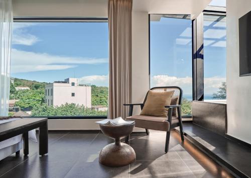 a living room with a chair and a large window at 涠洲岛隐拙山与澜海景酒店 in Weizhouxu
